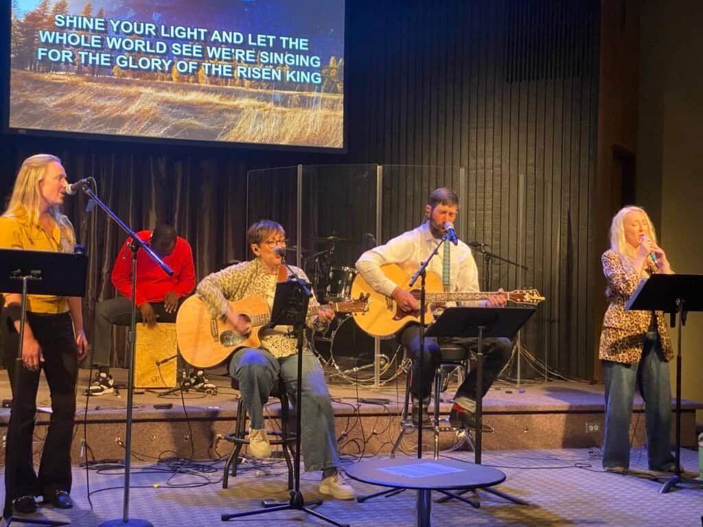 Musicians singing and playing guitars during a church worship service.