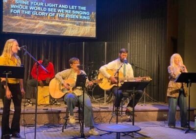 Musicians singing and playing guitars during a church worship service.